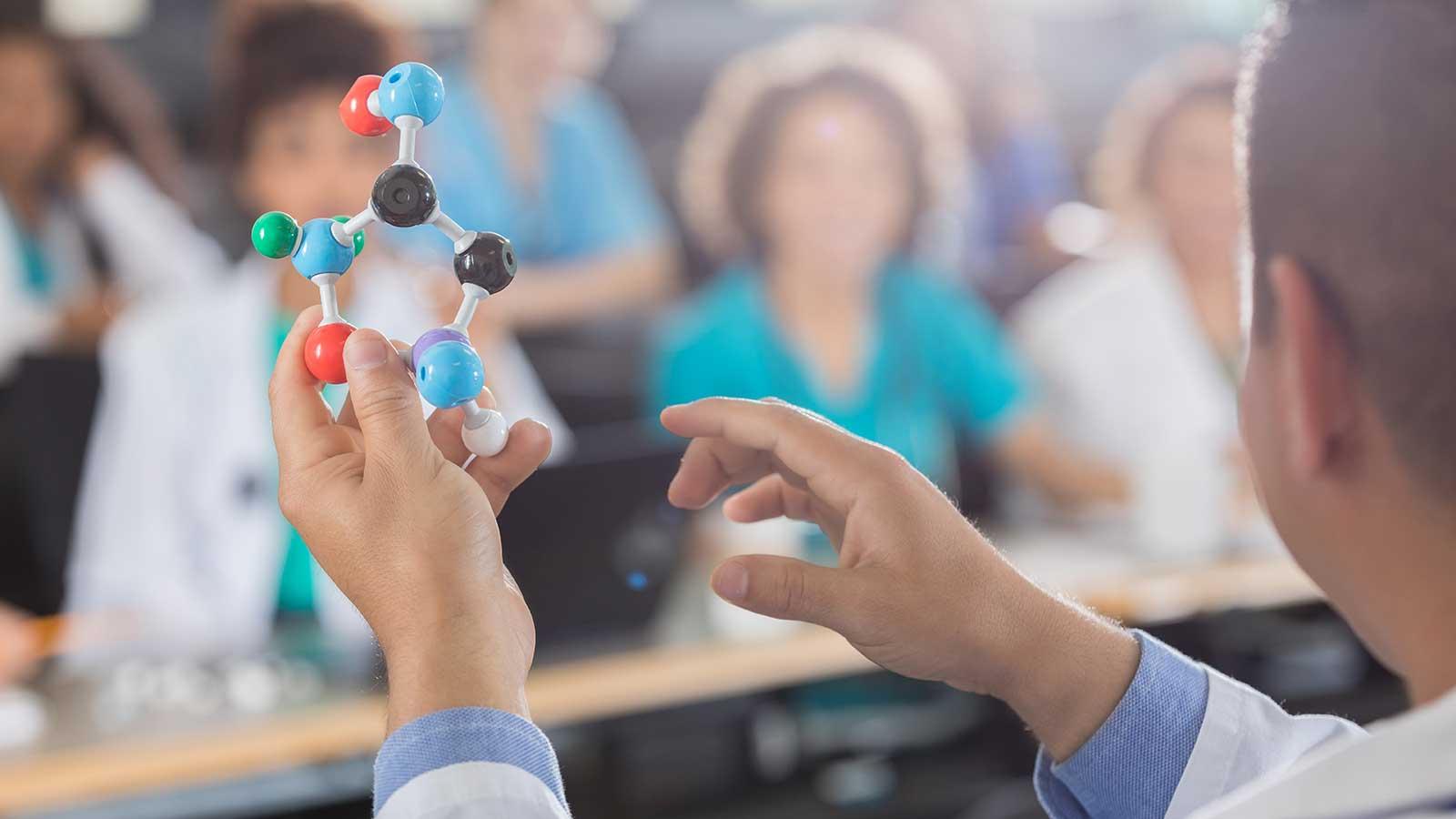Person holding plastic molecule bonds representing 生物学 program at Clarkson